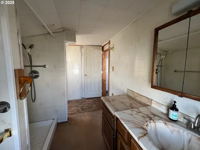 a view of an empty room with kitchen and a window