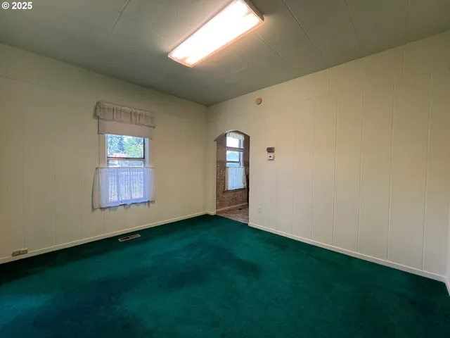a view of an empty room with window and stairs