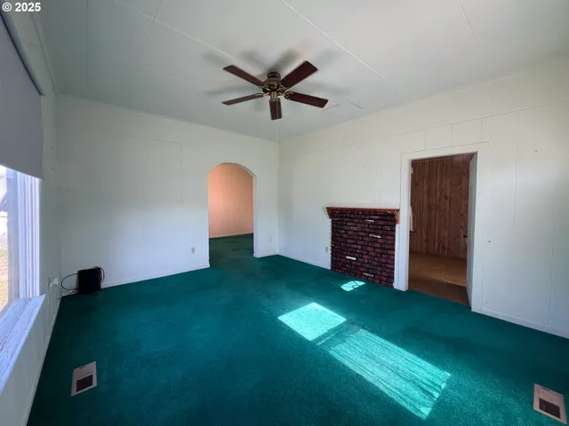 a view of an empty room with a fireplace and a window