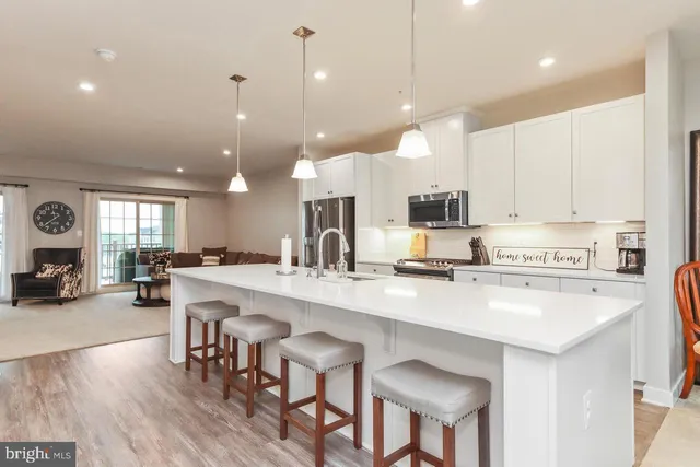 a kitchen with stainless steel appliances granite countertop a stove top oven a sink a refrigerator and white cabinets with wooden floor