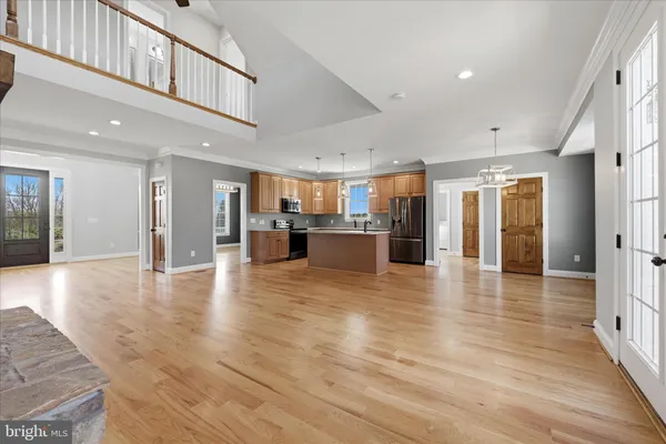 a view of an empty room with wooden floor and a ceiling fan