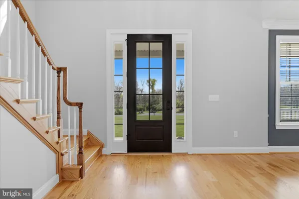 a view of an empty room with wooden floor and a ceiling fan