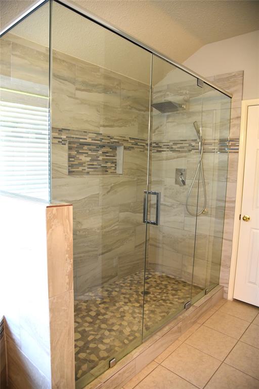 1526 Pebblestone Court Allen, TX 75002 - Photo 16 of 28 Frameless glass shower enclosure featuring a mosaic pebble floor and a rain showerhead