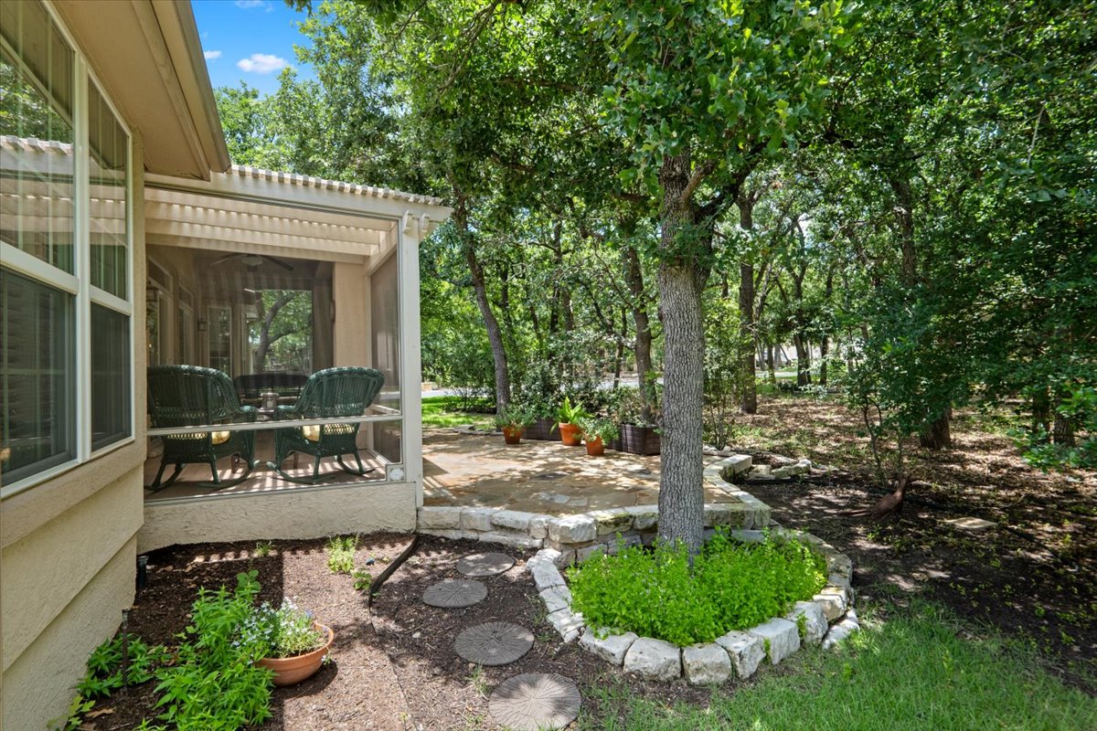 503 Breezeway Lane Georgetown, TX 78633 - Photo 33 of 38 Extended stone patio surrounded by mature trees and natural landscaping, creating a peaceful outdoor setting.