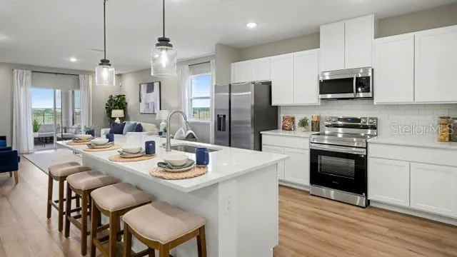 a kitchen with stainless steel appliances kitchen island granite countertop a sink a stove a microwave cabinets and dining table