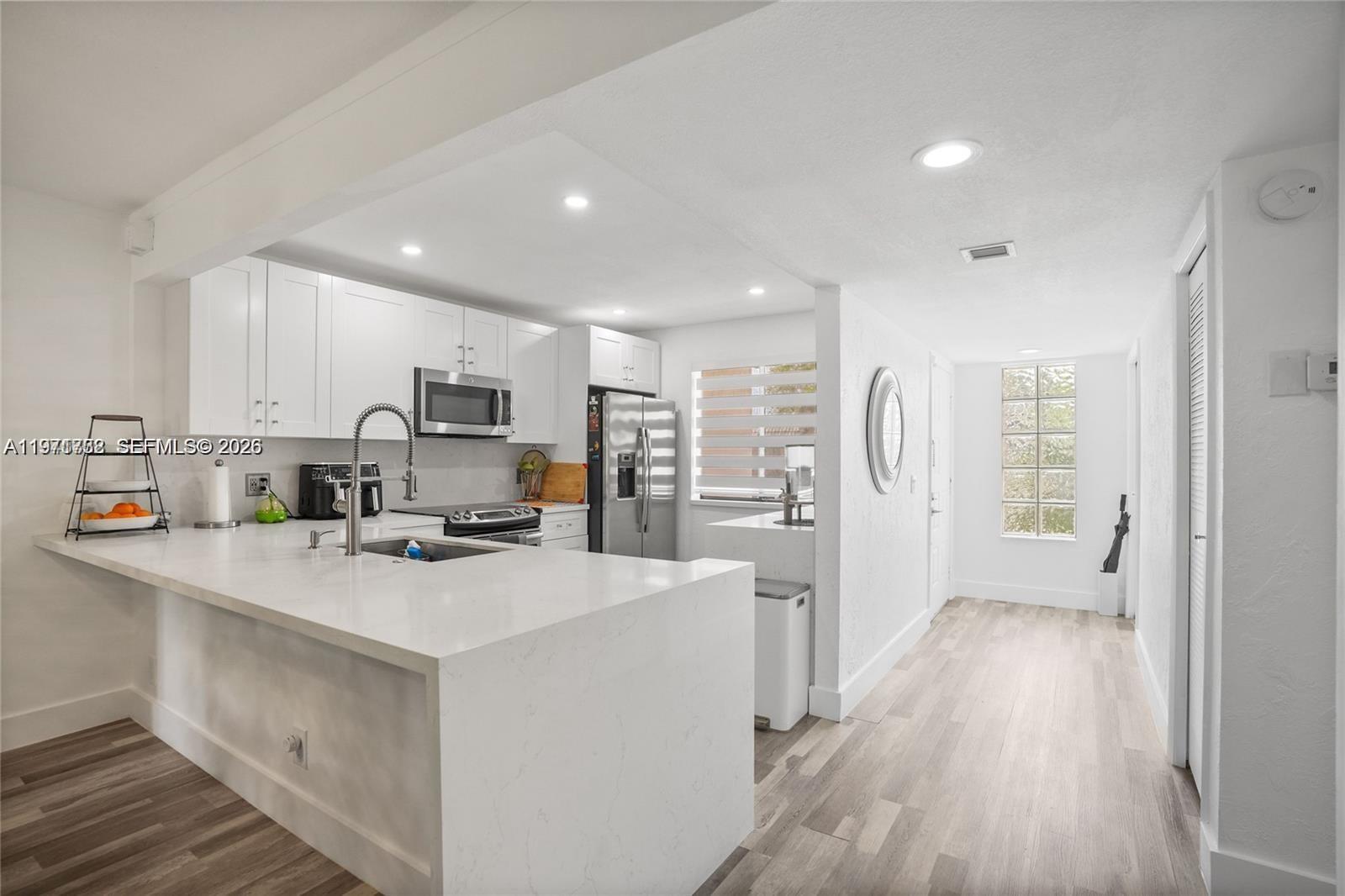 380 Racquet Club Road, Unit 204 Weston, FL 33326 - Photo 3 of 15 a kitchen that has a lot of cabinets a sink and wooden floor