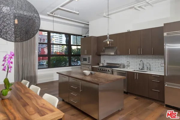 a kitchen with stainless steel appliances granite countertop a sink a stove and a wooden floors