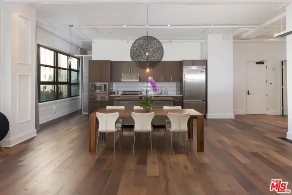 a dining room with wooden floor a chandelier a wooden table and chairs