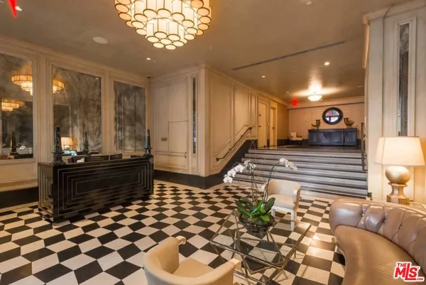 a living room with a black white checkered floor with couches chair and a coffee table