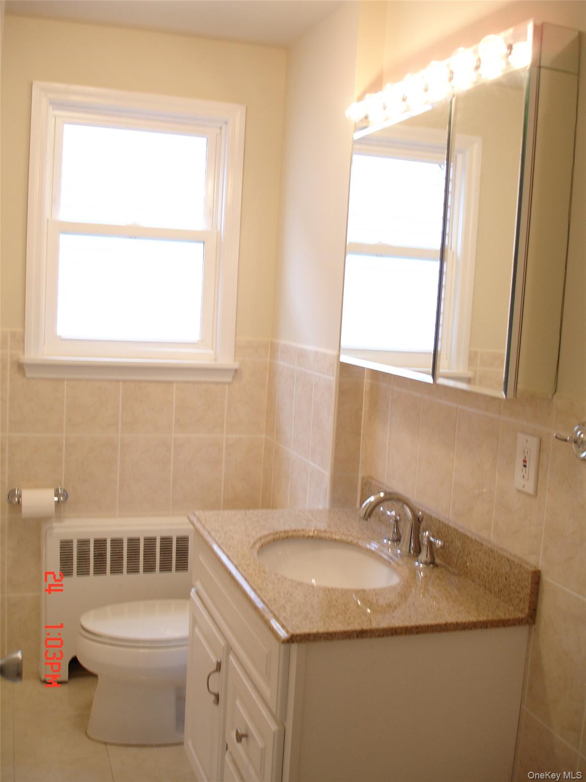 129 Maple Boulevard, Unit UPPR Long Beach, NY 11561 - Photo 11 of 13 a bathroom with a sink toilet and mirror