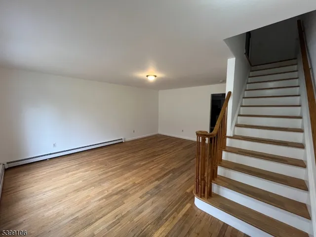 a view of a livingroom with wooden floor and stairs
