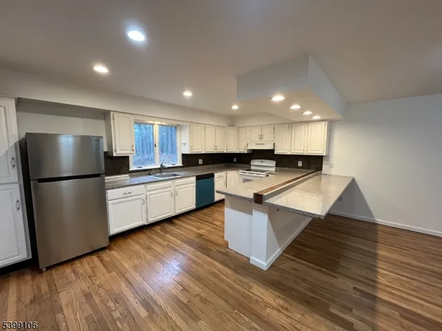 a kitchen with granite countertop a refrigerator and a stove top oven