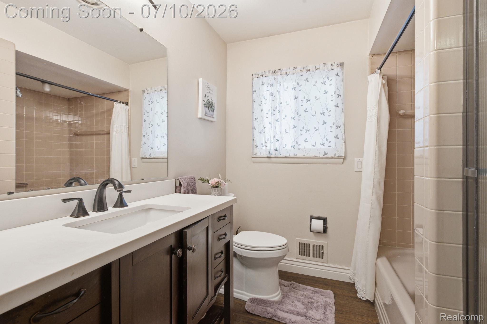 1501 River Road, Unit 301 St. Clair, MI 48079 - Photo 22 of 32 Bathroom featuring a dark wood-finish vanity with a white countertop and integrated sink, a rectangular mirror, and a window with sheer curtains