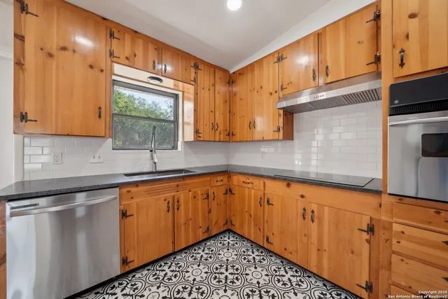 a kitchen with stainless steel appliances granite countertop a sink a stove and cabinets