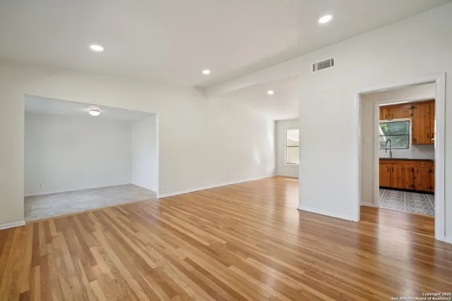 a view of an empty room with wooden floor and a window