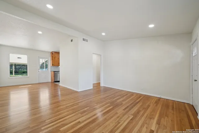 a view of empty room with wooden floor and window