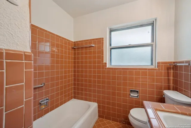 a bathroom with a toilet a window and a bathtub