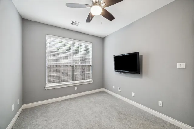 an empty room with windows and ceiling fan