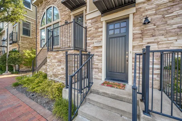 a view of a brick house with a small yard and floor to ceiling window and wooden fence