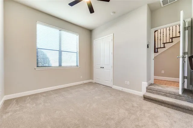 an empty room with chandelier fan and windows