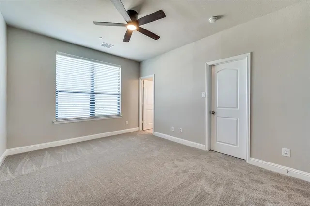 an empty room with windows and ceiling fan