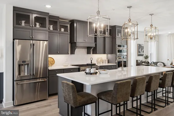 a kitchen with stainless steel appliances granite countertop a dining table chairs refrigerator and sink