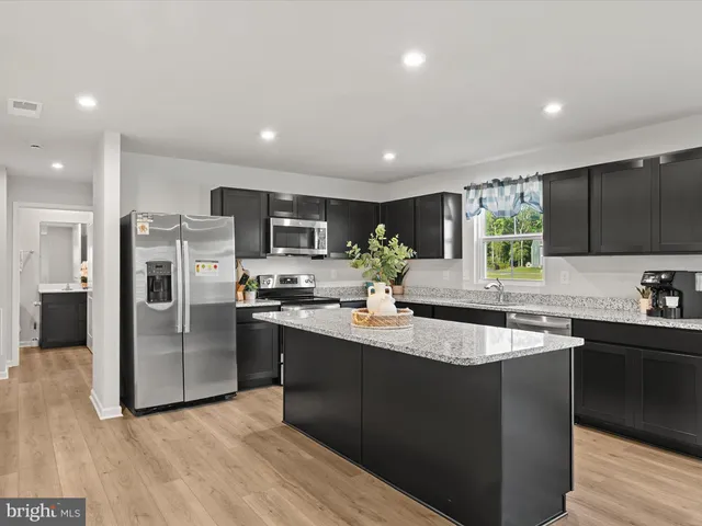 a kitchen with stainless steel appliances granite countertop a sink a stove a refrigerator cabinets and a kitchen island