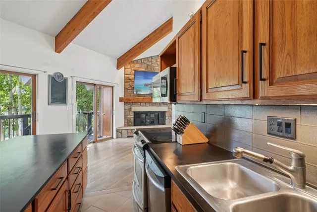 a kitchen with stainless steel appliances granite countertop a sink a stove and a refrigerator