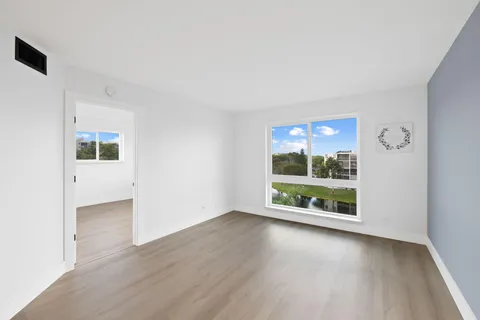 an empty room with floor to ceiling window and wooden floor