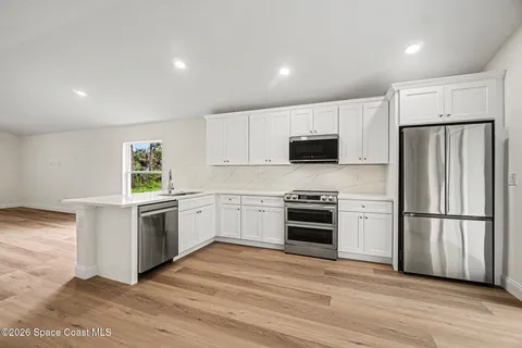 a kitchen with a refrigerator stove and wooden floor