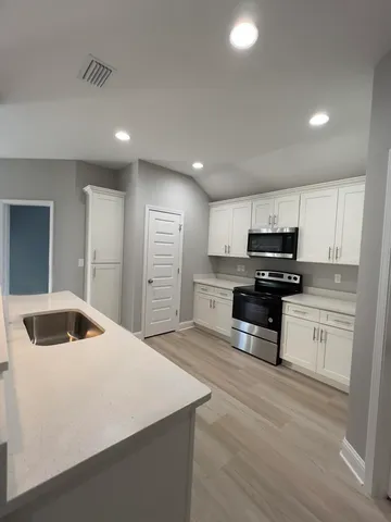 a kitchen with stainless steel appliances kitchen island a refrigerator sink and cabinets