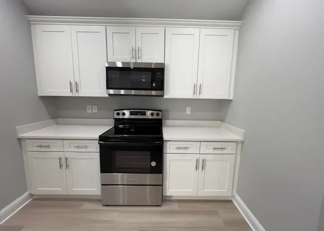 a kitchen with stainless steel appliances granite countertop white cabinets stove top oven and sink