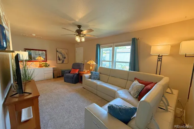a living room with furniture a ceiling fan and a window