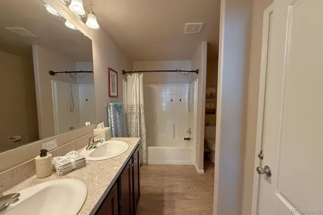 a bathroom with a granite countertop sink a mirror and a shower