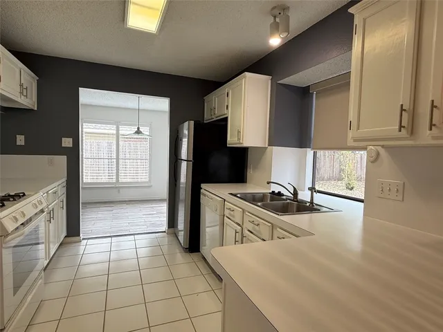 a kitchen with granite countertop a stove a sink and a refrigerator