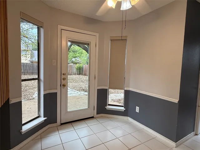 a view of an empty room with window and chandelier fan