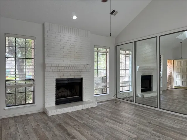 a view of an empty room with wooden floor fireplace and a window
