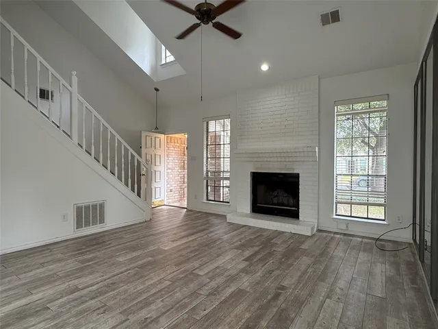 a view of an empty room with wooden floor fireplace and a window