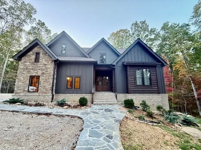 a front view of a house with a yard outdoor seating and covered with trees