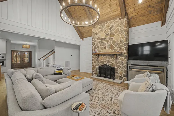 a kitchen with stainless steel appliances a stove a sink a microwave a refrigerator and white cabinets with wooden floor