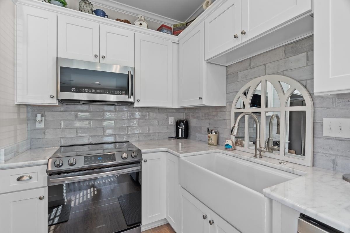 678 Morris Road Covington, TN 38019 - Photo 33 of 40 Kitchen featuring appliances with stainless steel finishes, tasteful backsplash, white cabinets, and light granite counters