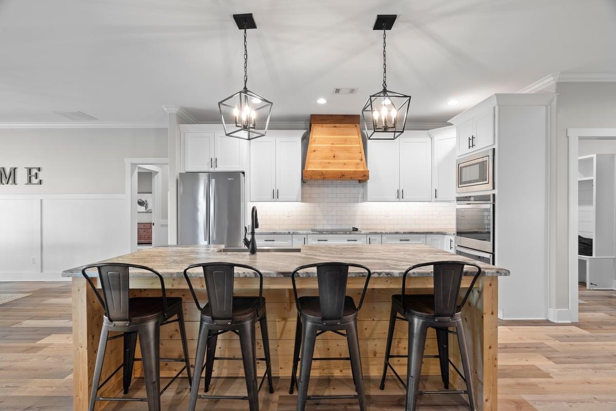 678 Morris Road Covington, TN 38019 - Photo 9 of 40 Kitchen featuring ornamental molding, pendant lighting, decorative backsplash, light wood-style flooring, and stainless steel appliances
