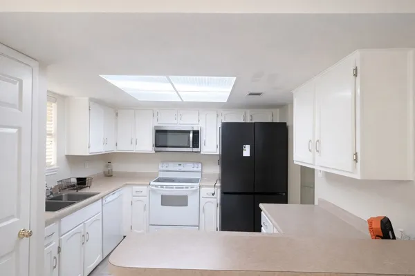 a kitchen with granite countertop white cabinets and white appliances
