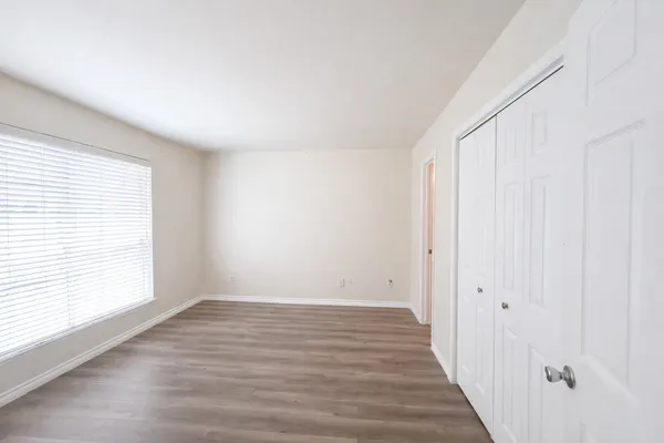 a view of an empty room with wooden floor and a window