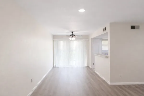 an empty room with wooden floor ceiling fan and windows