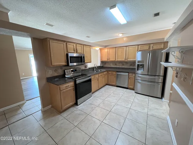 a kitchen with granite countertop a refrigerator and a stove top oven