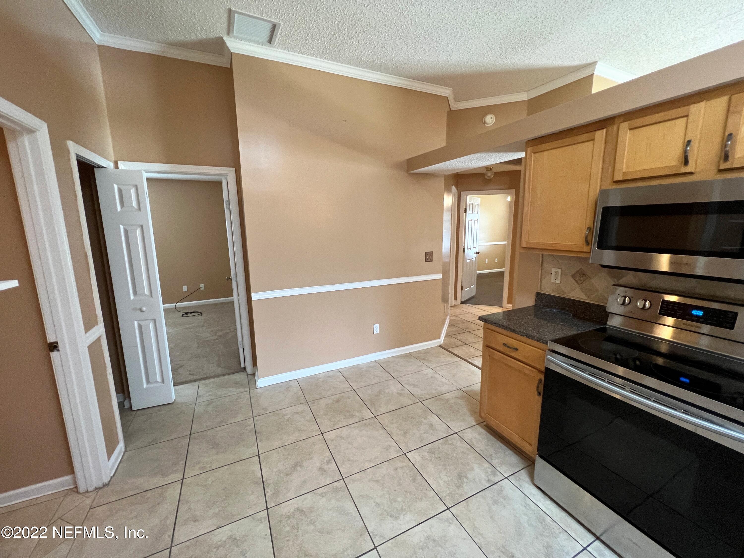 3742 Star Leaf Road West Jacksonville, FL 32210 - Photo 16 of 39 a view of a refrigerator in kitchen and an empty room in wooden floor