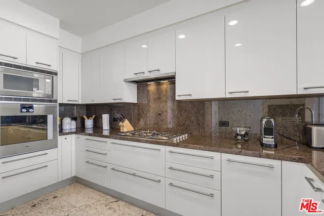 a kitchen with granite countertop a sink and a white cabinets