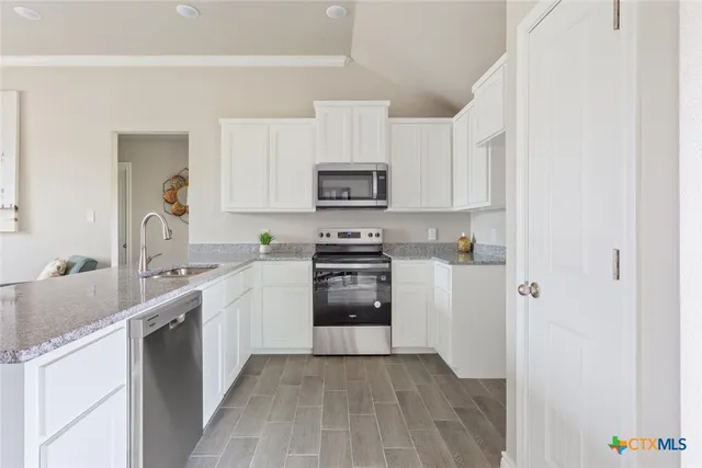 a kitchen with granite countertop a refrigerator stove and sink