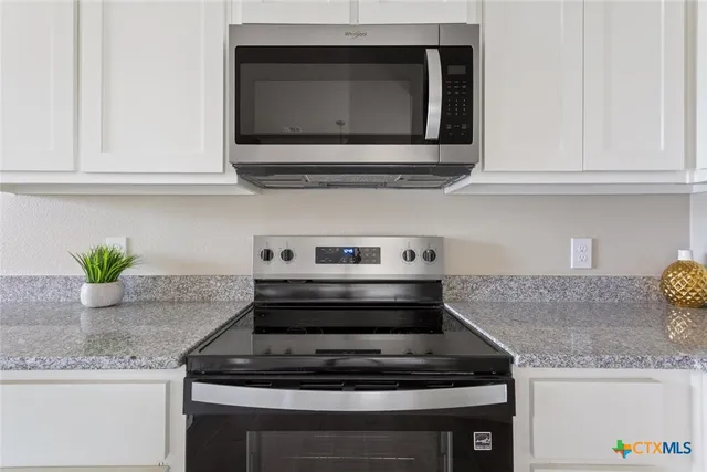 a kitchen with granite countertop white cabinets and a stove